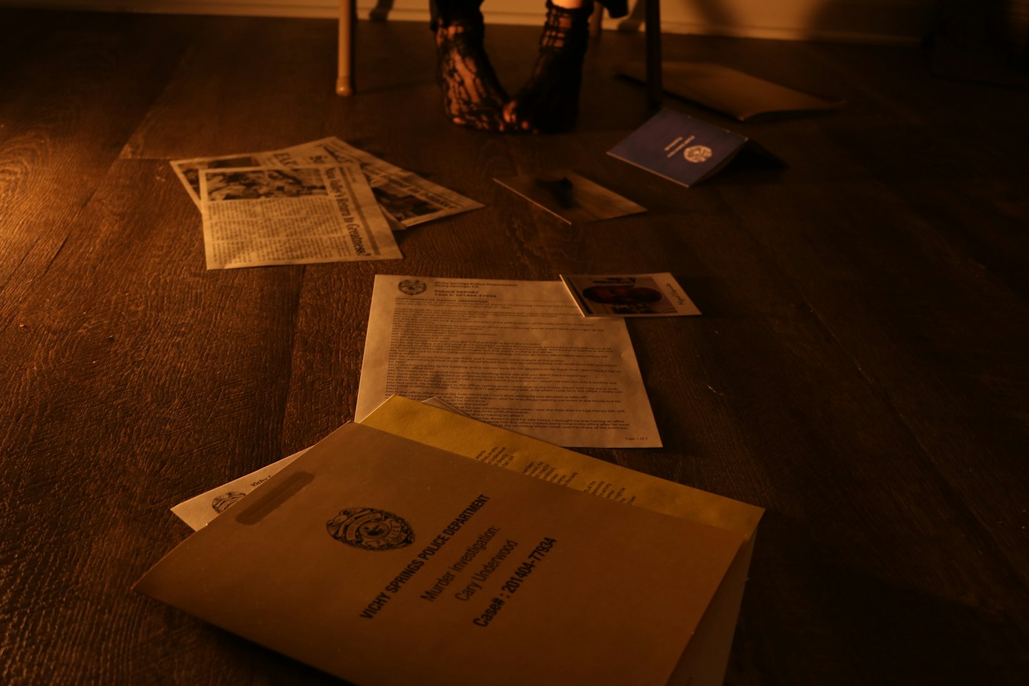 Documenti e cartelle con prove sparsi su un pavimento di legno.